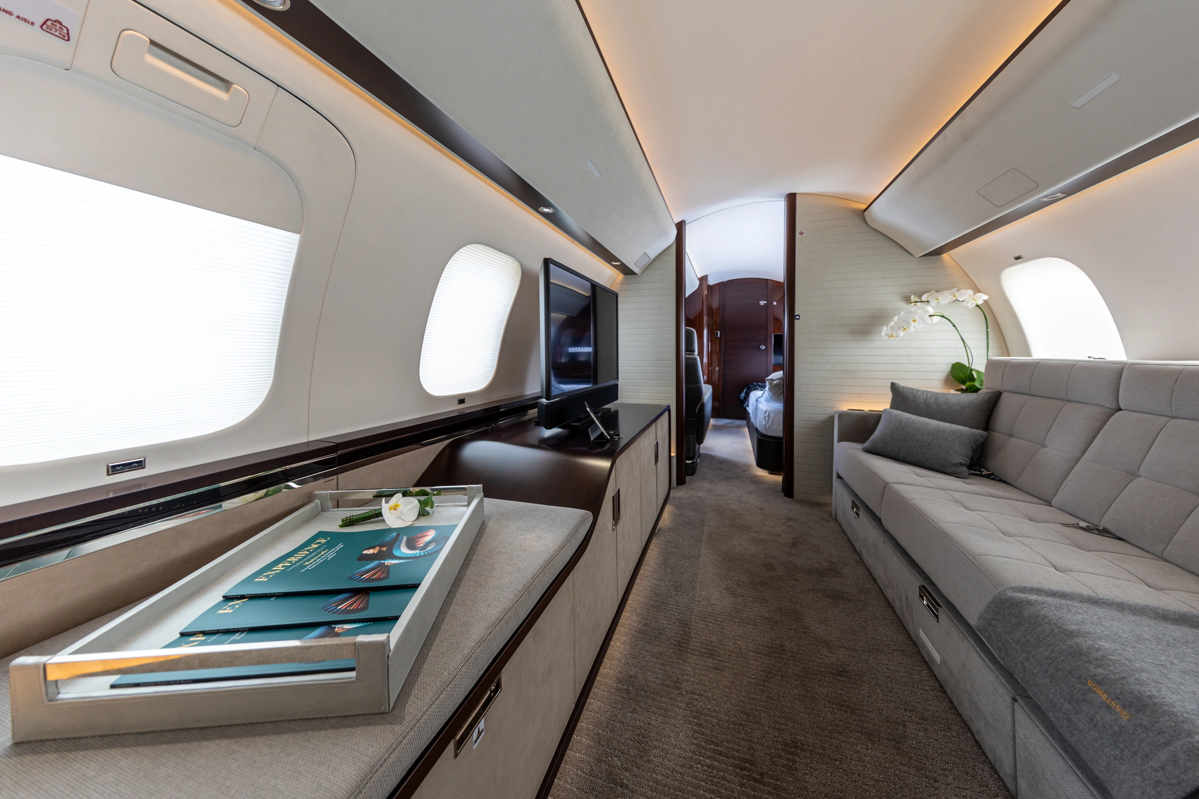 A private jet lounge with a cream sofa and warm lighting