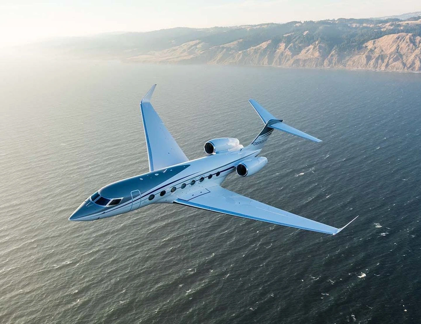 White Gulfstream business jet above a sunlit coastline
